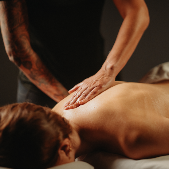 Massage des tissus profonds : mains sur le dos, personne allongée sur une table.