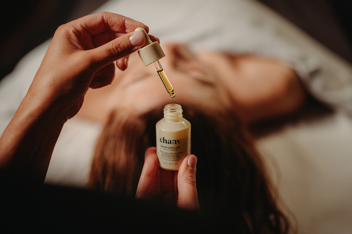 Huile de massage cheveux : flacon et pipette appliqués sur le cuir chevelu