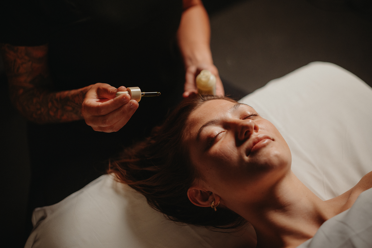 Massage du cuir chevelu : mains appliquant une huile sur les cheveux, cliente allongée