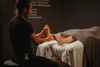 Massage réflexologie des pieds : praticien tenant et pressant une cheville sur table de massage