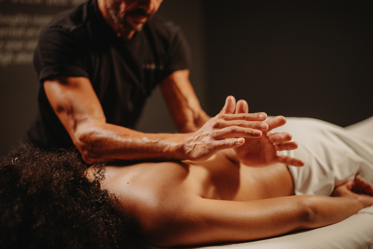 Massage Lomi-Lomi : mains sur le dos, praticien en séance sur table