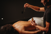 Massage signature avec huile : praticien appliquant l’huile sur le dos d’un client