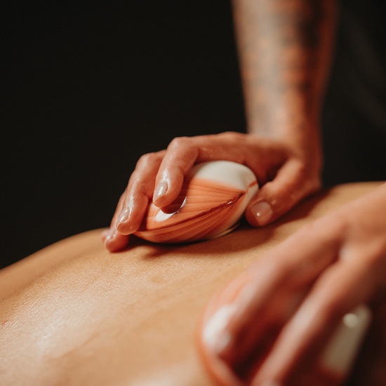 Massage de coquillages chauffants : coquillage chauffant rayé sur le dos, mains.