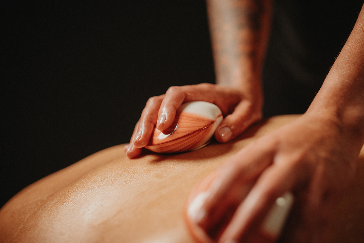 Massage de coquillages chauffants : coquillage chauffant rayé sur le dos, mains.