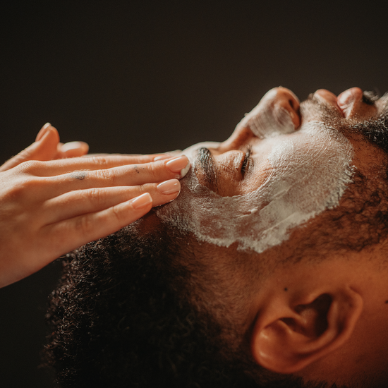 Soin du visage douceur : application du masque blanc sur le visage d’un homme allongé