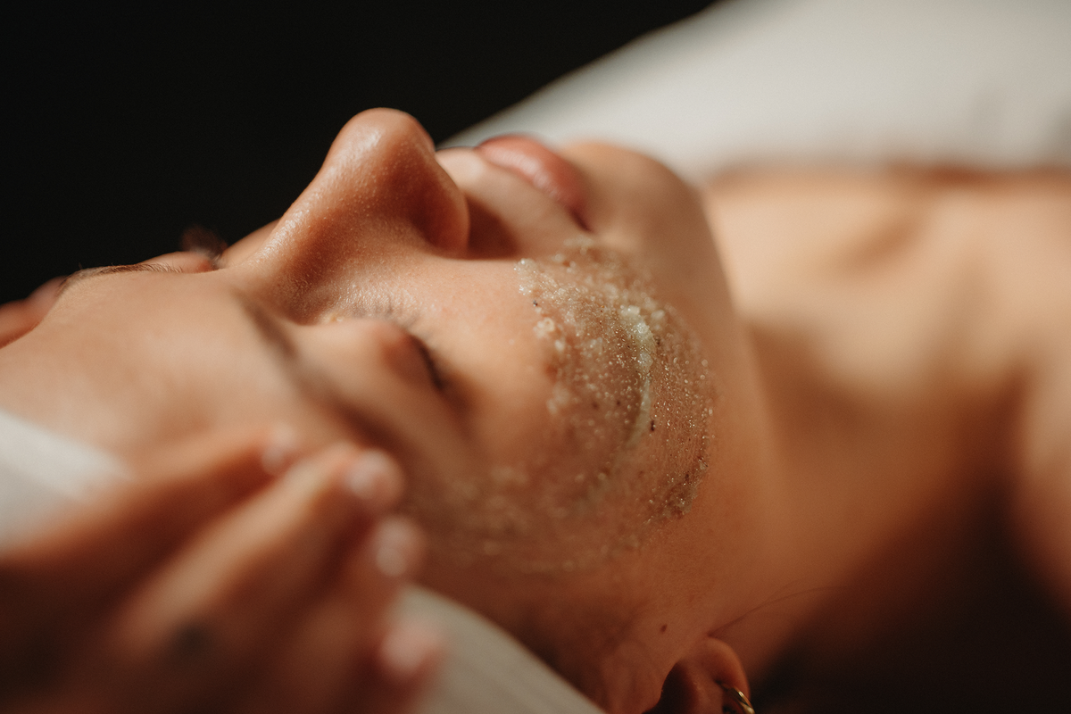 Soin visage hydratant : exfoliation aux grains sur le visage, mains en massage