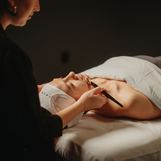 Soin du visage : mains appliquant un produit, personne allongée, serviette blanche