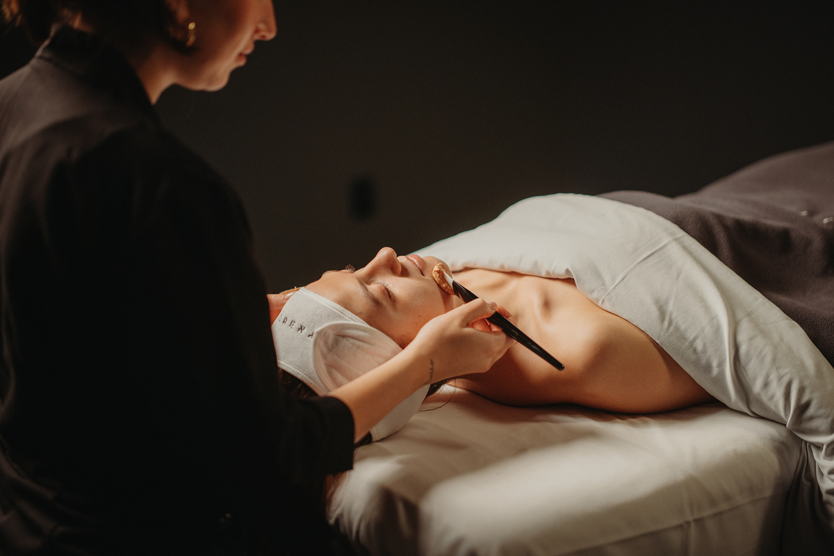 Soin du visage : mains appliquant un produit, personne allongée, serviette blanche