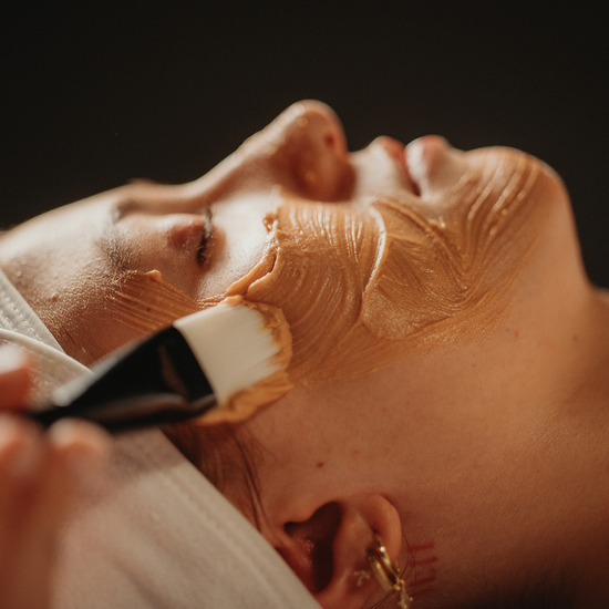 Soin du visage : masque-crème étalé au pinceau, visage partiellement couvert, gros plan.