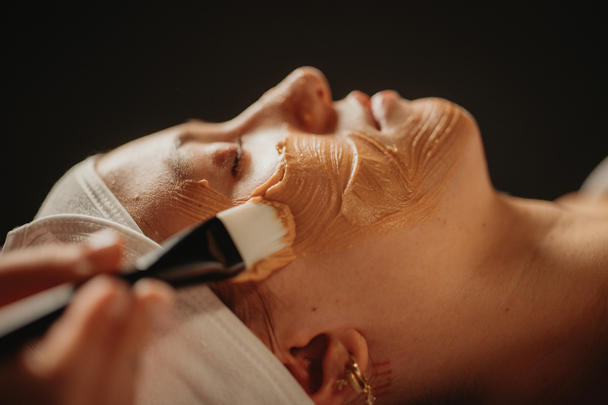 Soin du visage : masque-crème étalé au pinceau, visage partiellement couvert, gros plan.