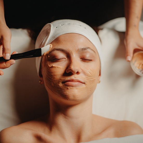 Soin du visage : crème appliquée sur le visage, yeux fermés, pinceau.