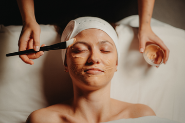 Soin du visage : crème appliquée sur le visage, yeux fermés, pinceau.