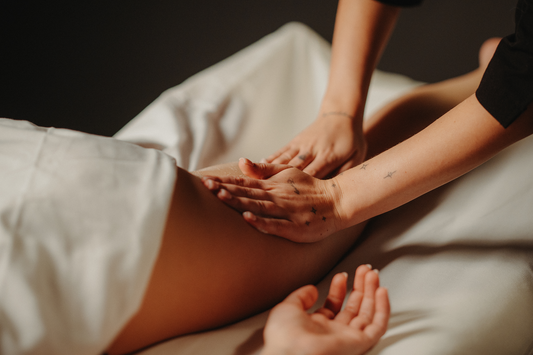Soin de silhouette naturelle : mains massant l’abdomen sur table, allongée