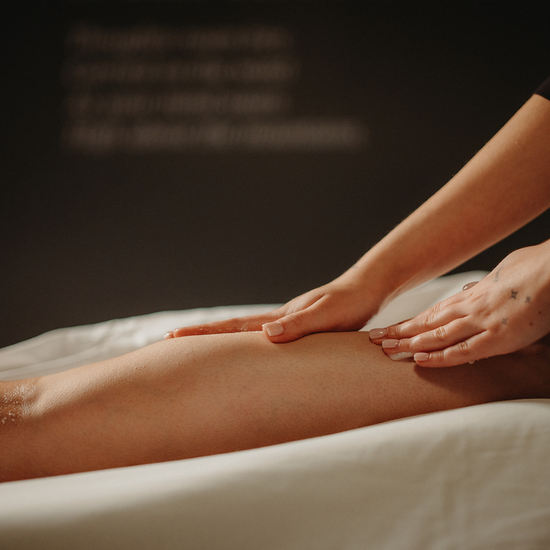 Massage des jambes, mains frottant une huile sur la jambe allongée
