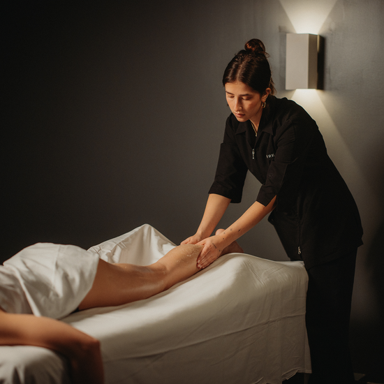 Massage des jambes sur table de soin, praticienne appliquant et massant la jambe