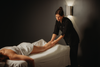 Massage des jambes sur table de soin, praticienne appliquant et massant la jambe