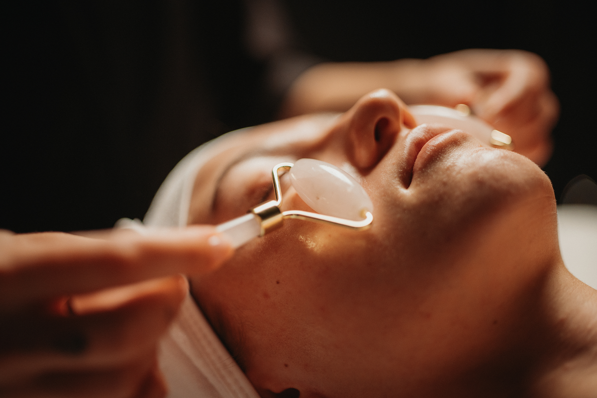Soin du visage iridescence bio : gua sha translucide sur le visage, mains en action