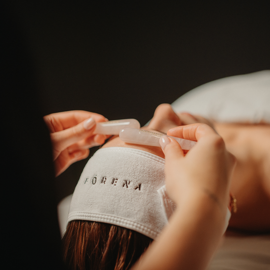 Soin du visage iridescence : gua sha translucide sur le front, serviette en éponge