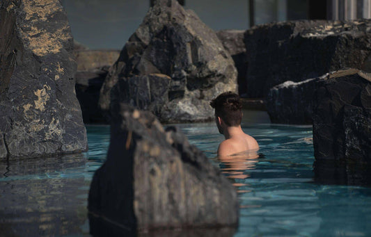 Carte-cadeau : personne dans une piscine entre rochers, buste hors de l’eau