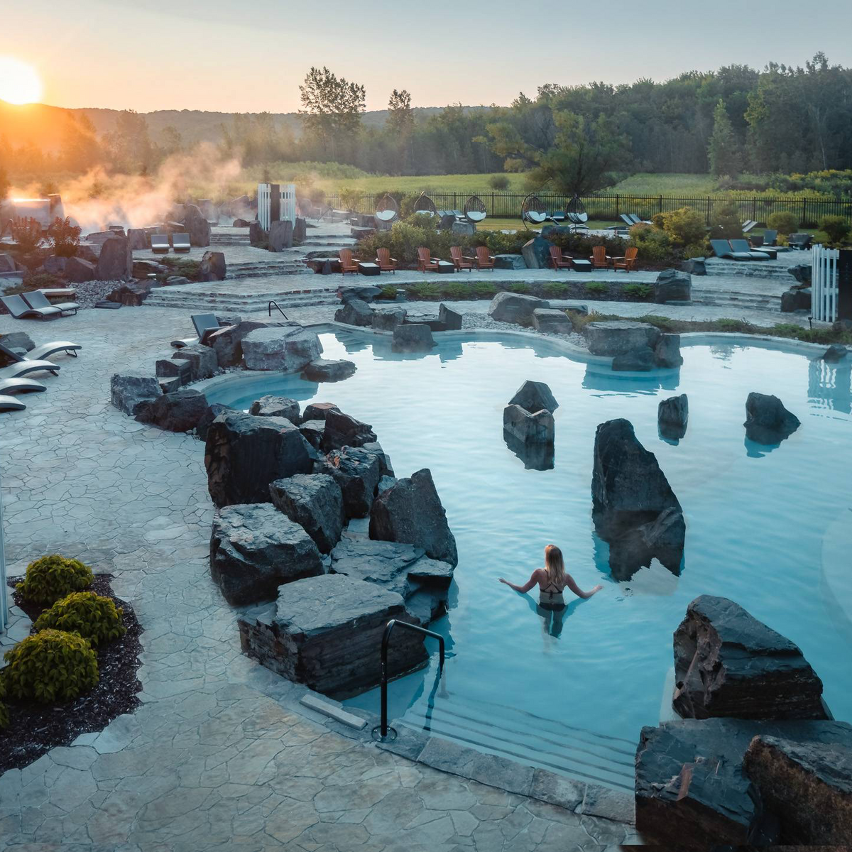 Bassin de spa extérieur avec eau bleue, rochers et bord en pierre.